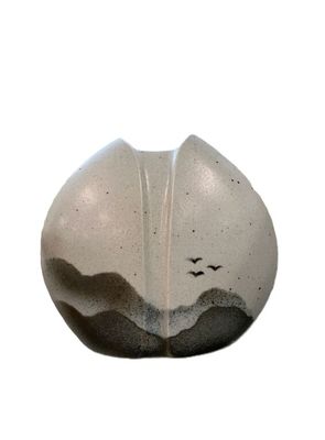 a white and black vase with birds flying in the sky