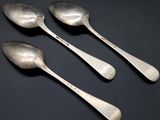 three silver spoons sitting on top of a table next to each other