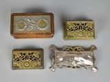 four pieces of silver and gold jewelry sitting on a white surface