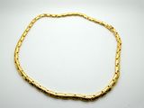 a gold bracelet with a twisted link on a white background