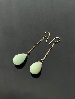 a pair of green tear shaped earrings on a black surface