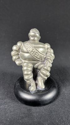 a silver figurine of a man sitting on top of a black base