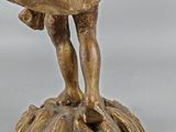 a statue of a man holding a bird on top of a tree stump