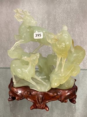 une sculpture en jade vert posée sur un socle, avec une étiquette de prix