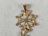 a close up of a gold cross pendant on a white surface