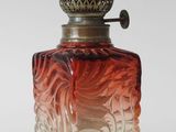 an image of a red and white glass perfume bottle on a white surface