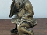 a statue of a man sitting on a wooden table
