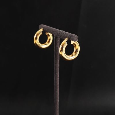 a pair of gold hoop earrings on a stand