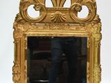 un miroir avec un cadre doré dans lequel se reflète un homme