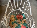 une chaise en osier blanc avec un coussin à fleurs