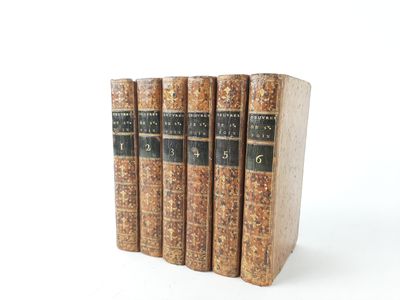 three old books sitting on top of each other on a white surface
