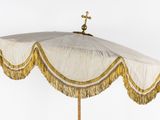 a white umbrella with gold fringes and a cross on top