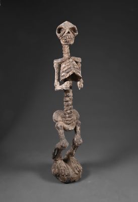 une statue représentant un squelette humain posé sur un rocher, coiffé d'un chapeau