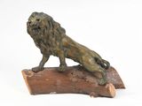 statue en bronze représentant un lion perché sur un tronc d'arbre, sur fond blanc