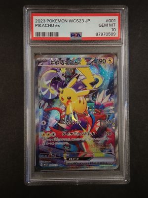 La carte Pokémon se trouve dans un étui en plastique transparent posé sur une surface noire.