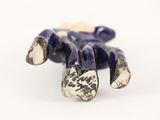 silver and lapis bead of a hand holding a flower on a white surface