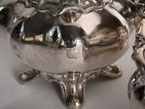 a silver tea pot sitting on a table next to a silver vase