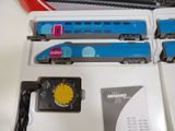 a blue and white train on the tracks next to other blue and white train cars