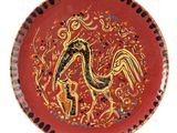 une assiette rouge sur laquelle est représenté un oiseau