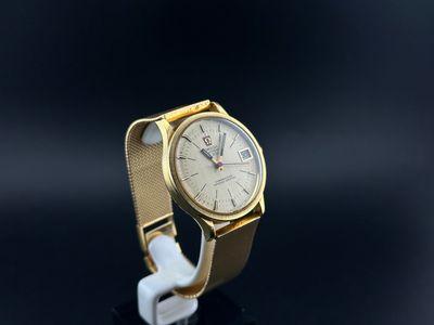 a close up of a gold wrist watch with a white strap