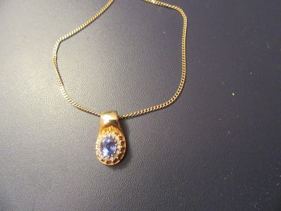 collier plaqué or avec un pendentif orné d'une pierre beige et bleue, monté sur une chaîne en or