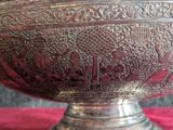 a silver bowl with a design on it on a red cloth