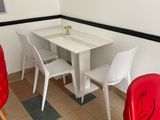 a table and chairs in a small room with a clock on the wall