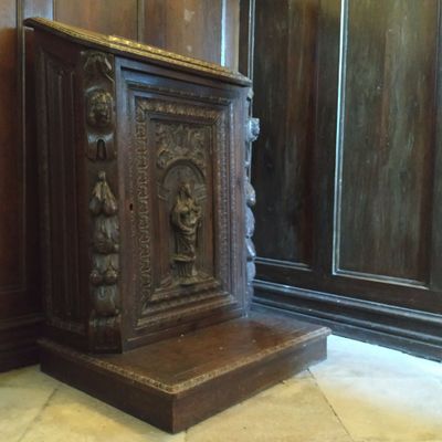 une armoire en bois ornée de sculptures, placée dans un coin de la pièce