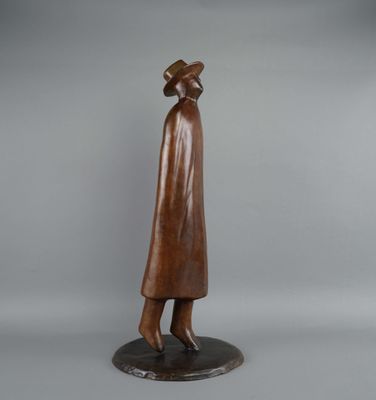 a bronze statue of a woman in a hat and coat