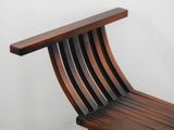 a wooden chair that is sitting against a white wall