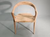 a wooden chair with a curved seat on a gray surface