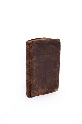 an old brown book sitting on top of a white surface