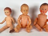 three dolls sitting next to each other on a white surface