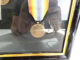 une photo d'un ours en peluche portant une médaille devant un miroir