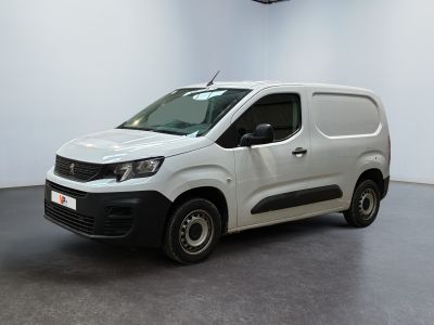La camionnette blanche est garée dans une grande pièce au sol noir.