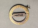 an old brass compass on a gray surface with a black handle