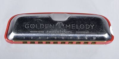 une image montrant un gros plan d'un harmonica dans un étui métallique