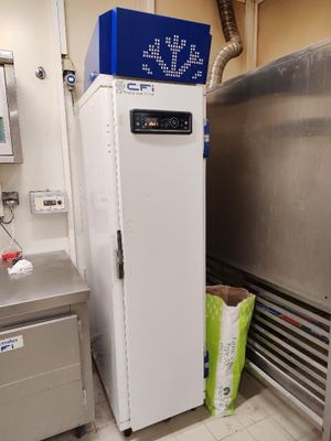 un réfrigérateur blanc dans une cuisine, avec une affiche bleue sur la porte