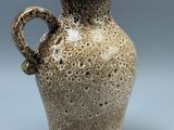 a brown vase with a handle on a gray background