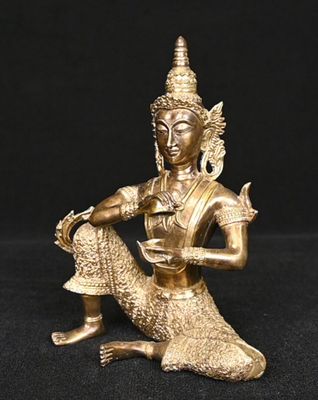 une statue en or représentant une femme assise sur un rocher, tenant un oiseau dans la main