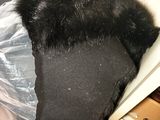 a black hat with a fur on it sitting on a plastic bag