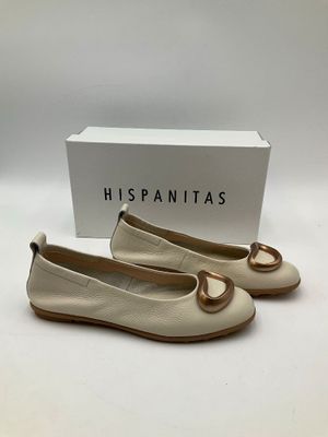 une paire de chaussures blanches ornées d'un anneau doré sur la pointe