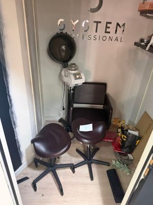 a photo of a hair salon with a chair and a hair dryer