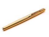 un stylo doré posé sur une surface blanche, avec un fond blanc