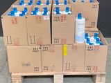 Plusieurs cartons d'eau sont empilés sur une palette devant un mur noir