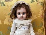 a doll that is sitting on a chair with a name tag on it