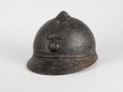 un vieux casque repose sur une surface blanche, devant un fond blanc