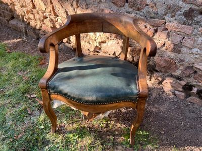 une chaise en bois avec une assise en cuir, placée devant un mur en pierre