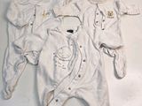 three baby clothes laid out on a white surface