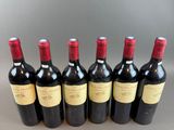 six bottles of red wine lined up in a row